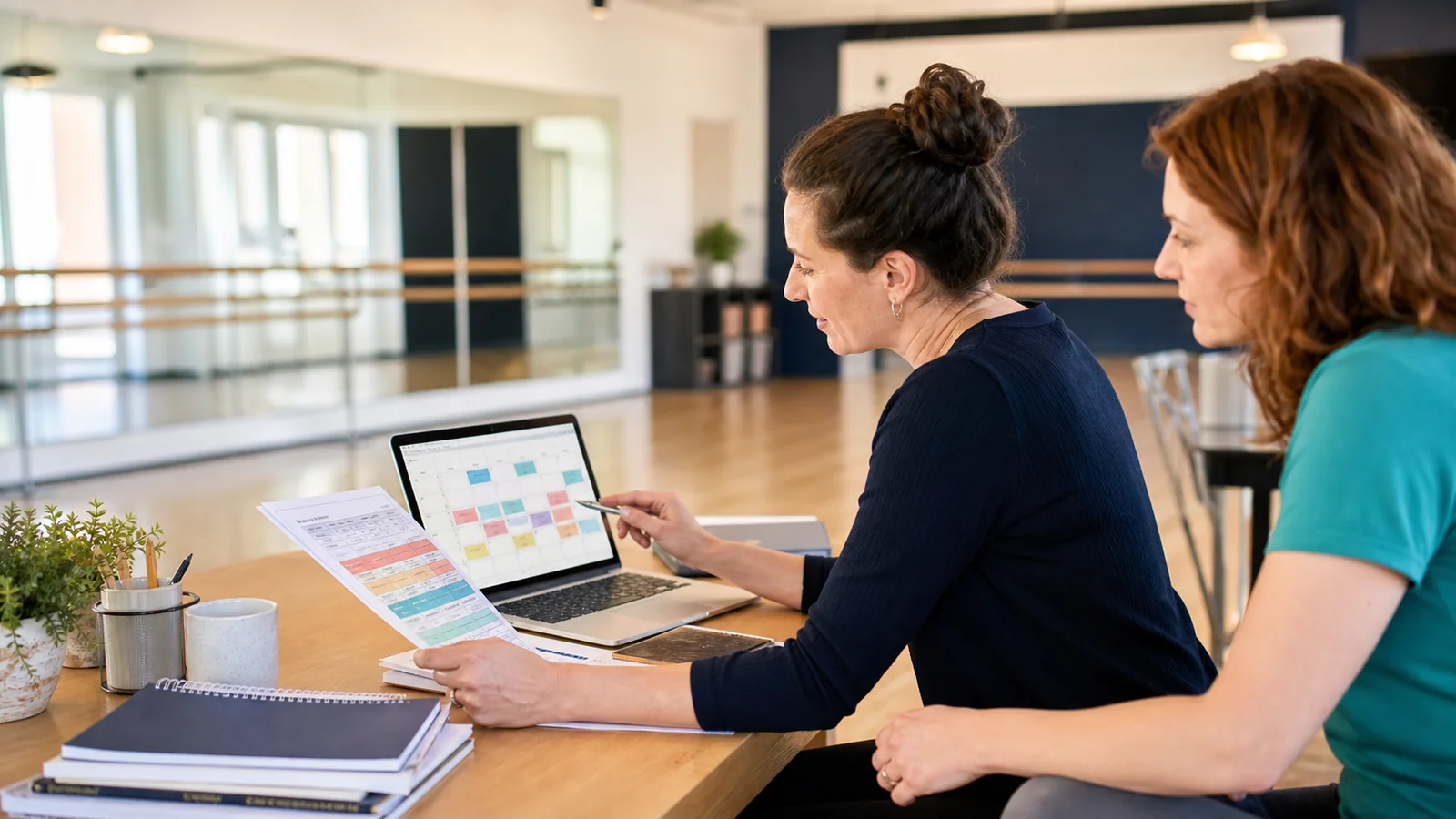 A parent and the studio owner looking over the class schedule together at the front desk